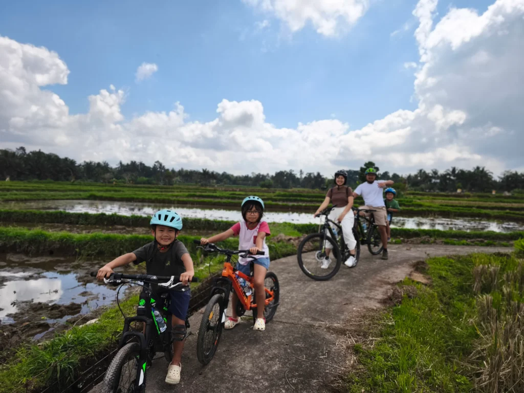 Family enjoying a cycling tour in Ubud through rice fields with a friendly local guide family cycling in ubud rice field kids cycling in ubud village